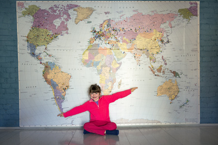 Little girl flying under a big World mapの写真素材