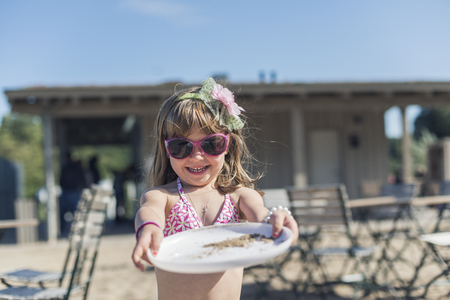 Little blond girl playing with her freesbe at the beachの写真素材