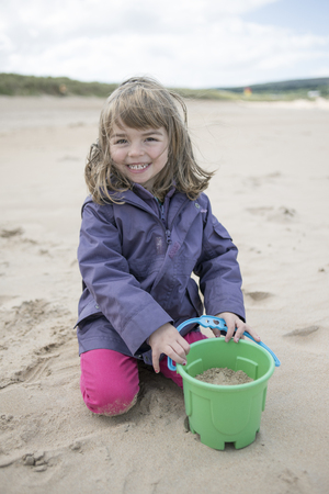 Little girl playing at the beach in winterの写真素材