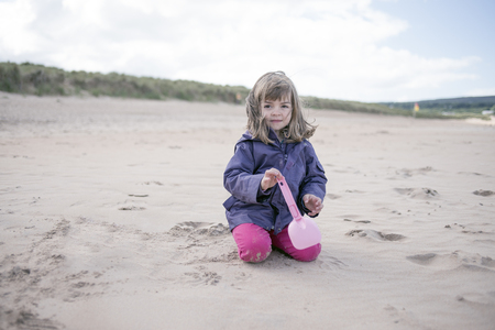 Little girl playing at the beach in winterの写真素材