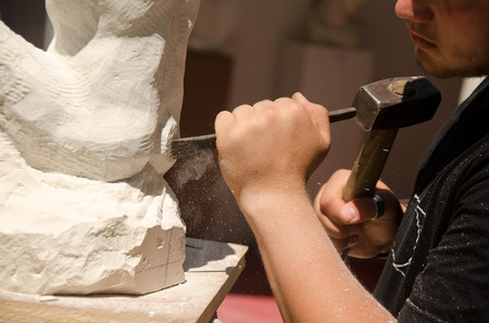 Man with hammer working on stone statueの写真素材