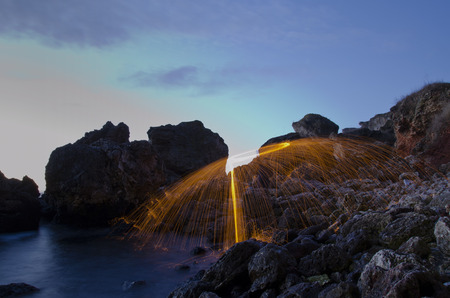 Amazing fire light painting in the sea shoreの写真素材