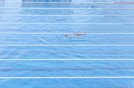 Woman swimming in the swimming pool. Blue background.