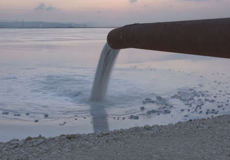 Industrial wastewater is discharged from pipe into the water