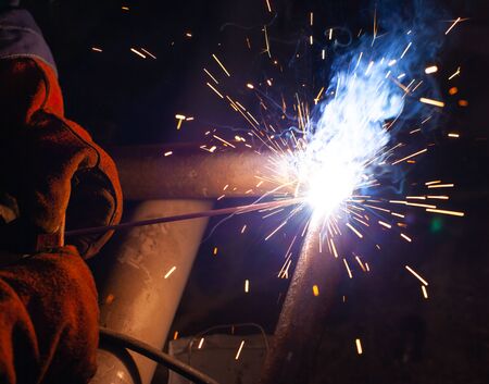 Electric welding works on the pipeline in a dark room