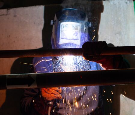 Electric welding works on the pipeline in a dark room