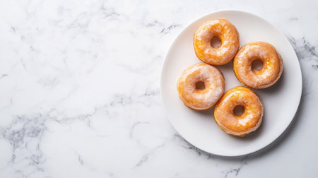 A delightful arrangement of fresh glazed donuts on a white plate against a marble background. Perfect for breakfast or dessert.の素材
