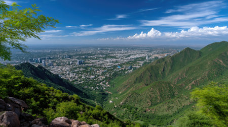 An expansive view showcasing a dynamic city framed by verdant mountains. The bright blue sky adds vibrancy, offering a perfect escape into nature and urban life.の素材