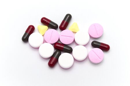 Prescription drugs, pills, capsules and tablets of different colors all mixed in. On white...