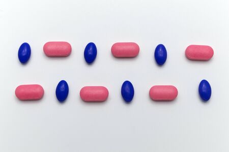 Many different medical pills between blue and pink color on white background, Top view.