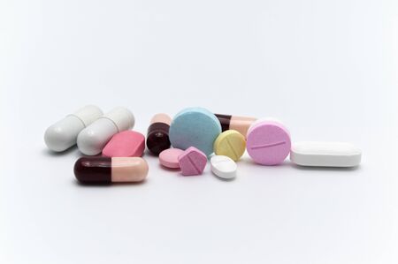 Prescription drugs, pills, capsules and tablets of different colors all mixed in. On white...
