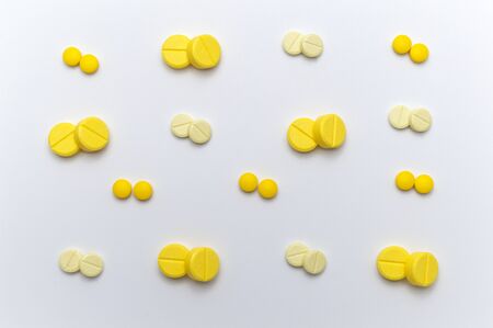 Prescription drugs or medicine pills and tablets of yellow colors shades. On white background. Top view.の写真素材