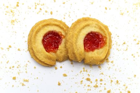 Butter cookies strawberry jam topping flavored and some crumbs all of around. Crunchy delicious...