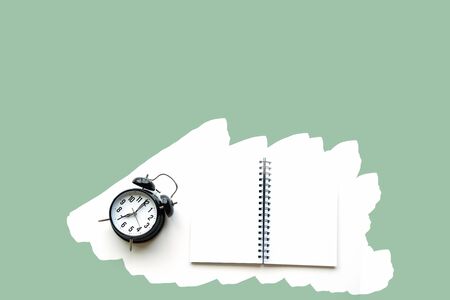 Alarm clock next to a notebookの写真素材