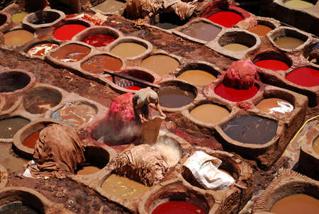 A Moroccan man hard at work in the traditional tanning process of leather production in Fes, Morocco