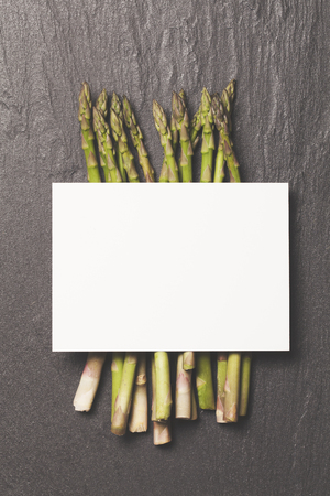 Fresh asparagus on a rustic slate background with a blank white labelの写真素材