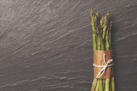 Fresh asparagus tied in a bunch on a rustic slate backgroundの写真素材