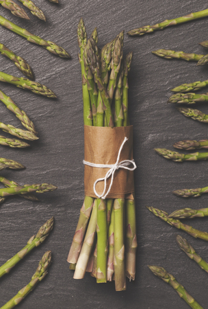 Fresh asparagus tied in a bunch on a rustic slate backgroundの写真素材