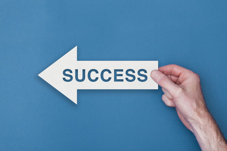 Success arrow direction held on a blue backgroundの写真素材