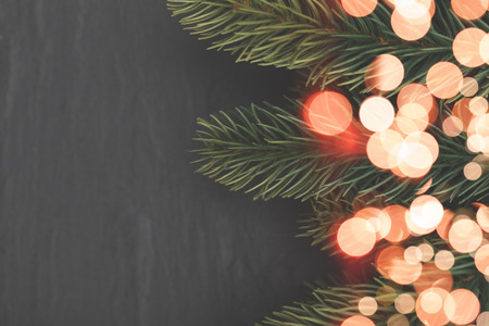 Christmas background with fir tree branches and bokeh blurred fairy lightsの写真素材