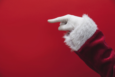 Santa Claus hand pointing finger against a red backgroundの写真素材