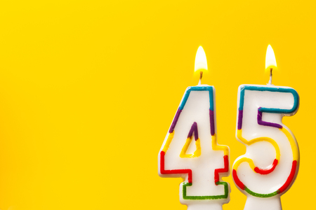 Number 45 birthday celebration candle against a bright yellow backgroundの写真素材