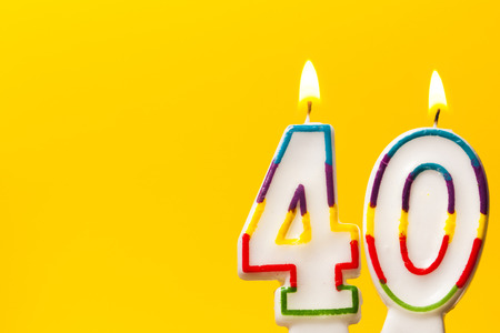 Number 40 birthday celebration candle against a bright yellow backgroundの写真素材