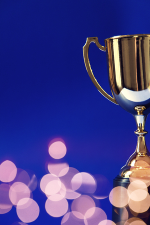 Gold winners trophy cup with bokeh blurred lightsの写真素材