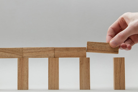 Male hand stacking wooden blocks. Business development and growth concept