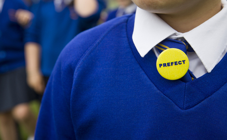 Young person in blue school uniform with a prefect badgeの写真素材