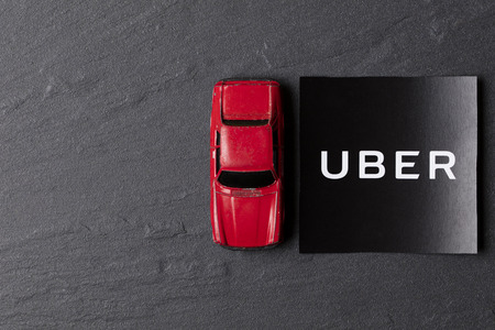 A photograph of  the Uber logo and toy car. Uber is a popular taxi style transport service application, founded in 2009のeditorial素材