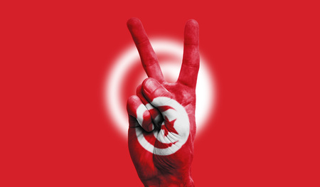 Tunisia national flag painted onto a male hand showing a victory, peace, strength signの写真素材