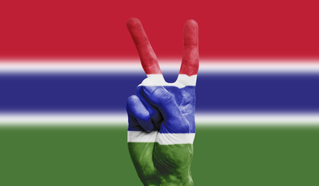 Gambia national flag painted onto a male hand showing a victory, peace, strength signの写真素材