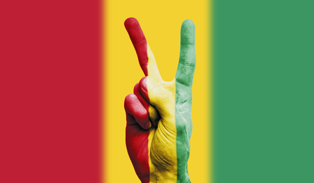 Guinea national flag painted onto a male hand showing a victory, peace, strength signの写真素材