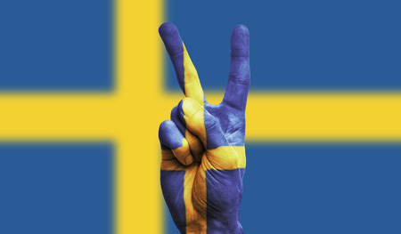 Sweden national flag painted onto a male hand showing a victory, peace, strength signの写真素材