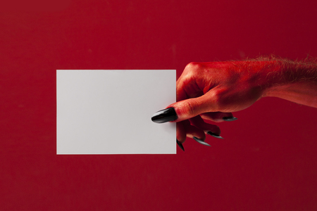 Red spooky devil hand holing blank paper. Halloween party backgroundの写真素材