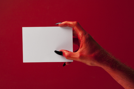 Red spooky devil hand holing blank paper. Halloween party backgroundの写真素材