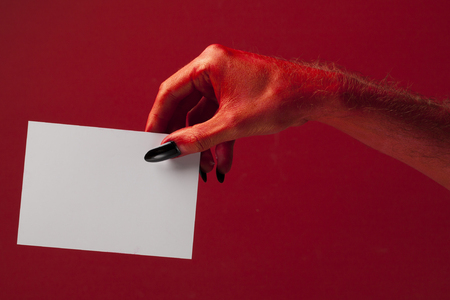 Red spooky devil hand holing blank paper. Halloween party backgroundの写真素材