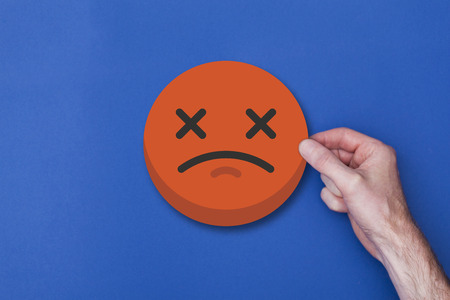 Male hand holding a emoji emoticon unhappy smiley head iconの写真素材