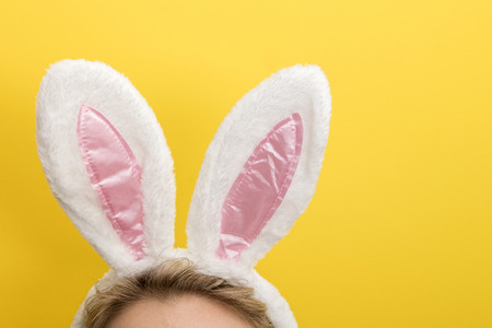 Easter bunny ears. Female wearing white bunny ears costume against a bright yellow backgroundの写真素材