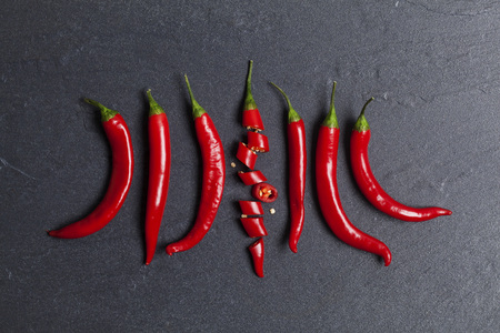 Red fresh chili pepper chopped into pieces on a dark slate backgroundの写真素材