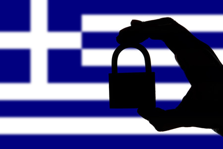 Greece security. Silhouette of hand holding a padlock over national flagの写真素材