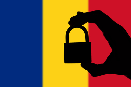 Romania security. Silhouette of hand holding a padlock over national flagの写真素材