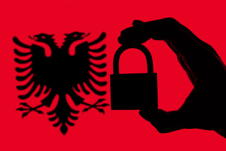 Albania security. Silhouette of hand holding a padlock over national flagの写真素材
