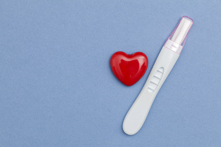 Pregnancy test with a red heart on a blue backgroundの写真素材