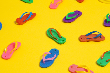 collection of colourful summer flip flop sandals on a bright yellow backgroundの写真素材