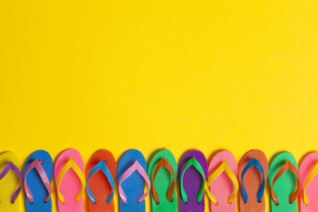 collection of colourful summer flip flop sandals on a bright yellow backgroundの写真素材