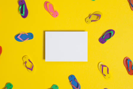 Summer flip flop sandals with a blank white sign on a bright yellow backgroundの写真素材