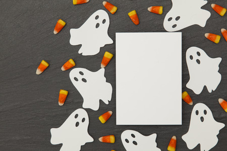 Halloween background with ghosts and candy corn on a slate background