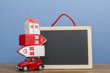 LONDON, UK - JANUARY 19th 2018: A toy oy car carrying a stack of houses against a blank blackboard. Moving house conceptのeditorial素材